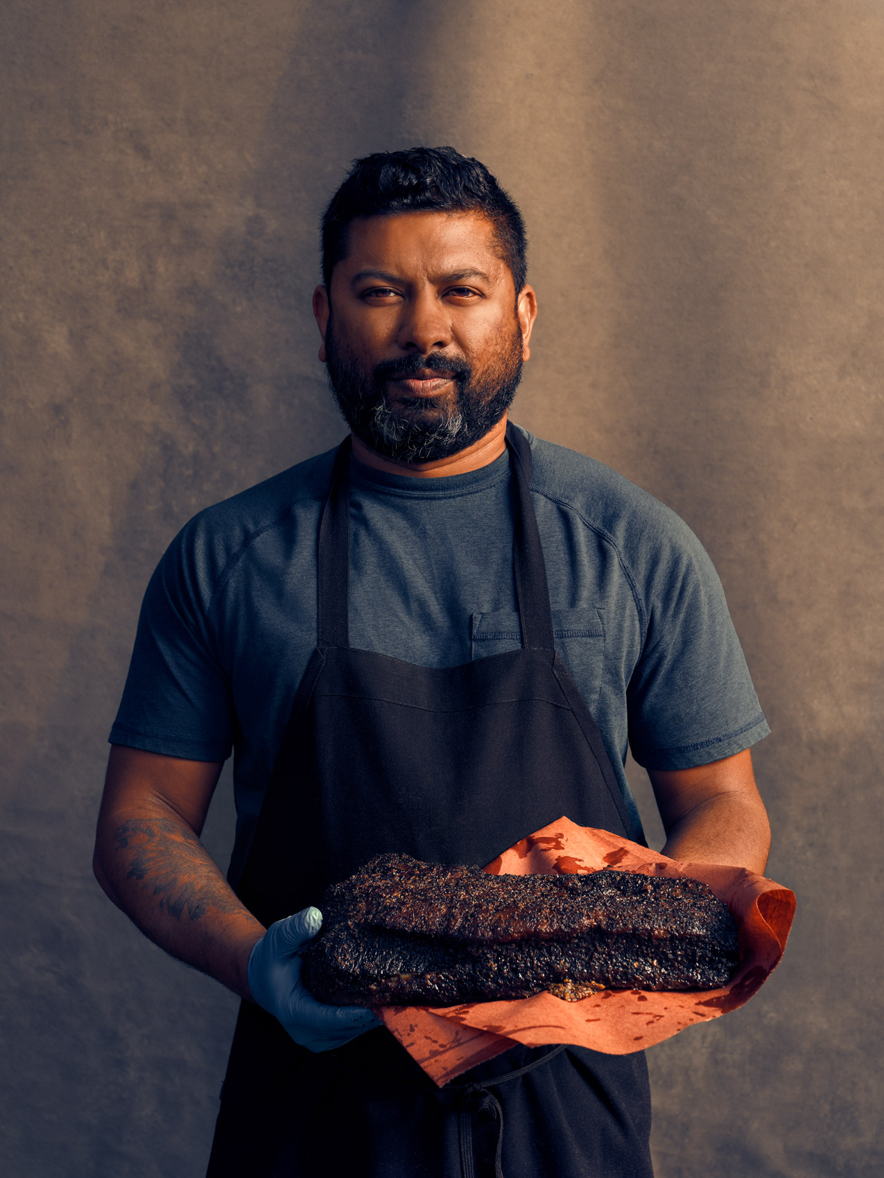 Buffalo NY chef Ryan Fernandez of Southern Junction BBQ holding a smoked brisket outside of his restaurant
